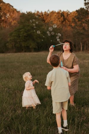 People playing with soap bubbles in a golden field at sunset.