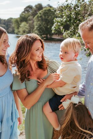 Candid family moment captured by waterside with blooming flowers in background.