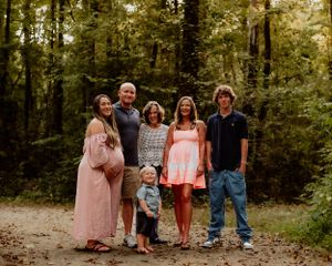 A family group photo session captured in a wooded outdoor setting.