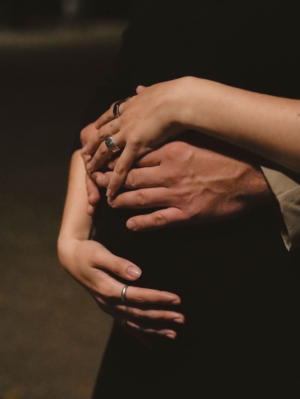 A man and a woman are embracing the pregnant woman's belly.
