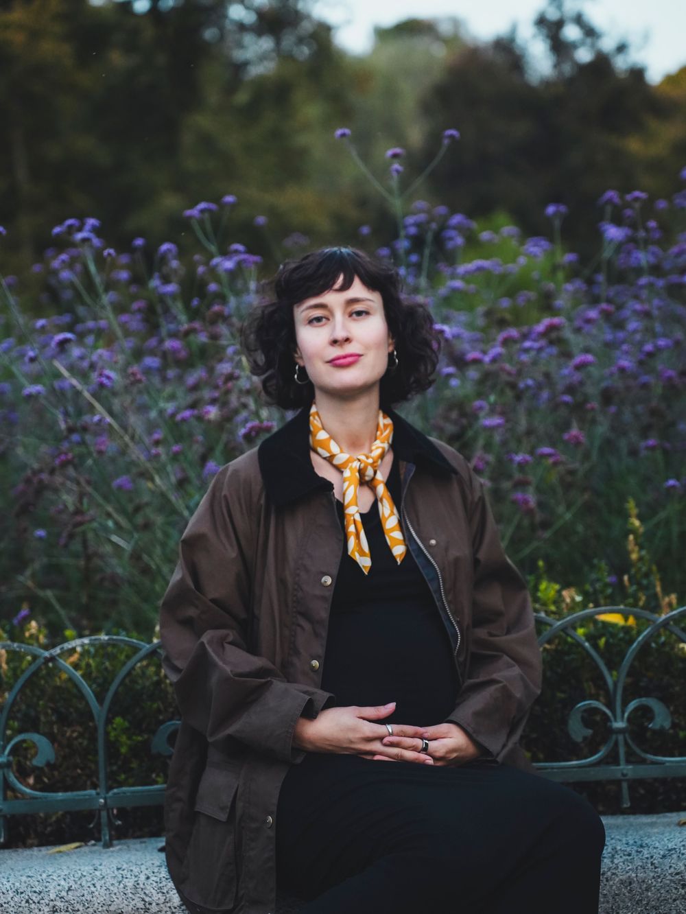 A pregnant woman sits on the bench.