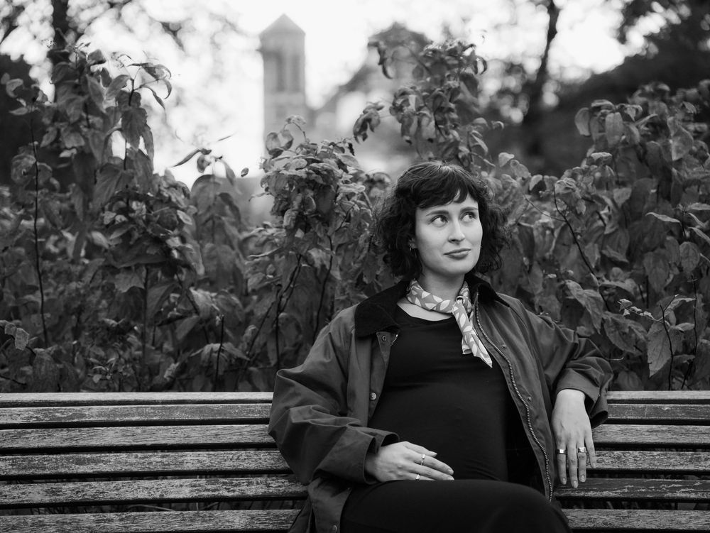 A pregnant woman sits on the bench.