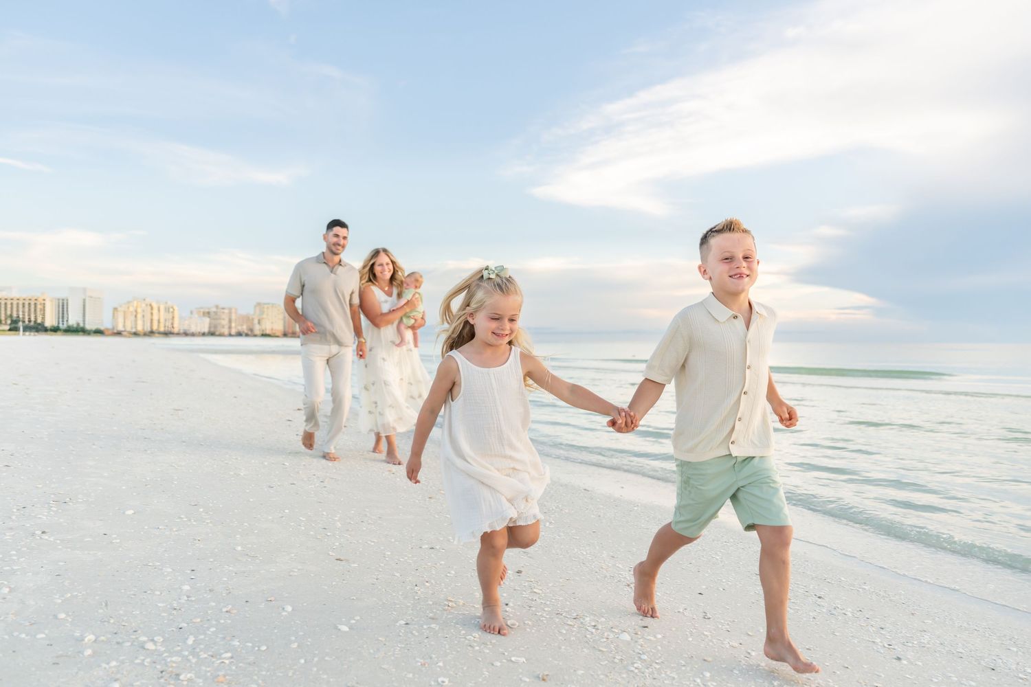 A family enjoys a playful moment together on a beach at sunset with cloudy skies with Florida Beach Photographer