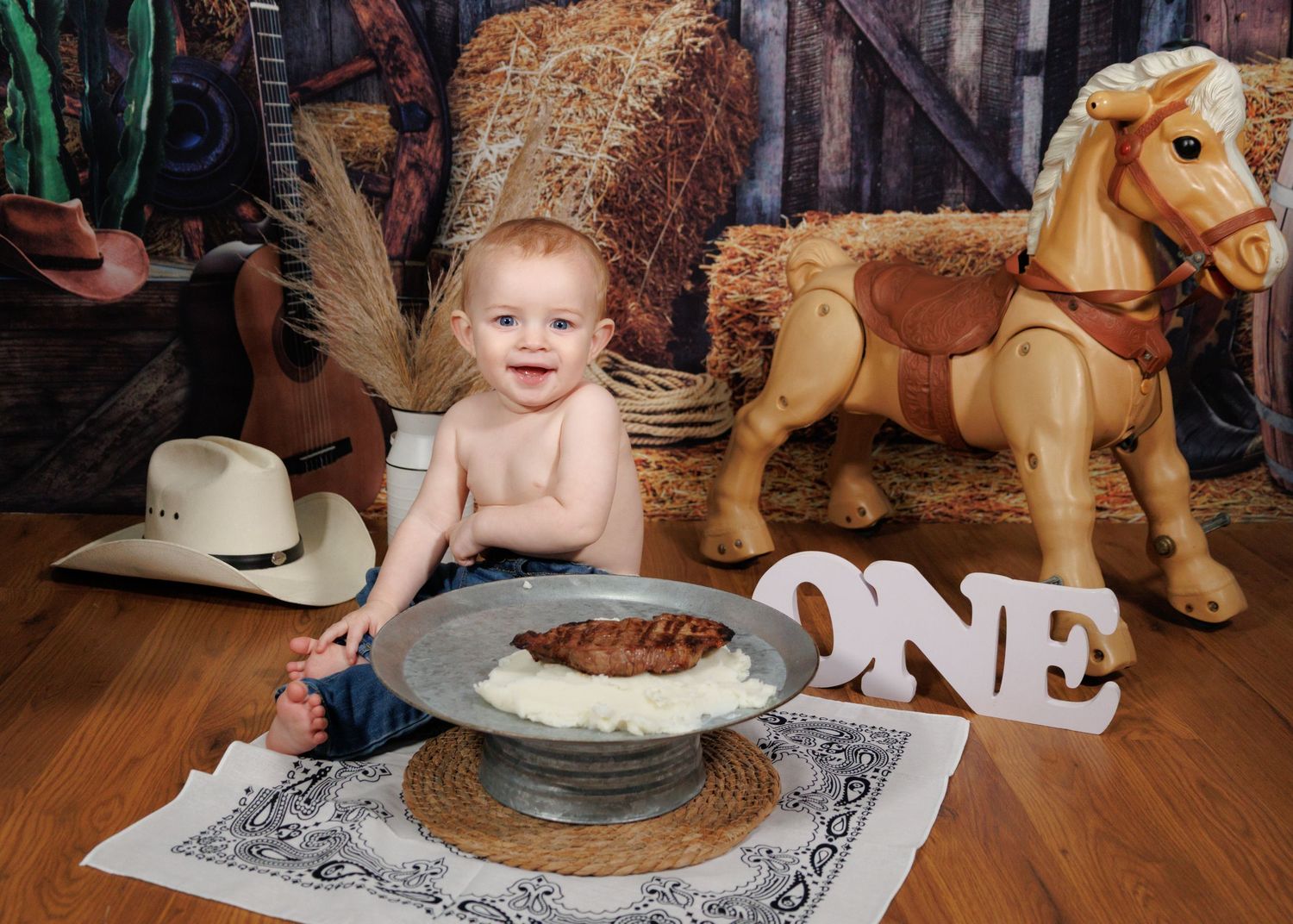 A cake smash setup with rustic decor featuring a rocking horse and cowboy hat.