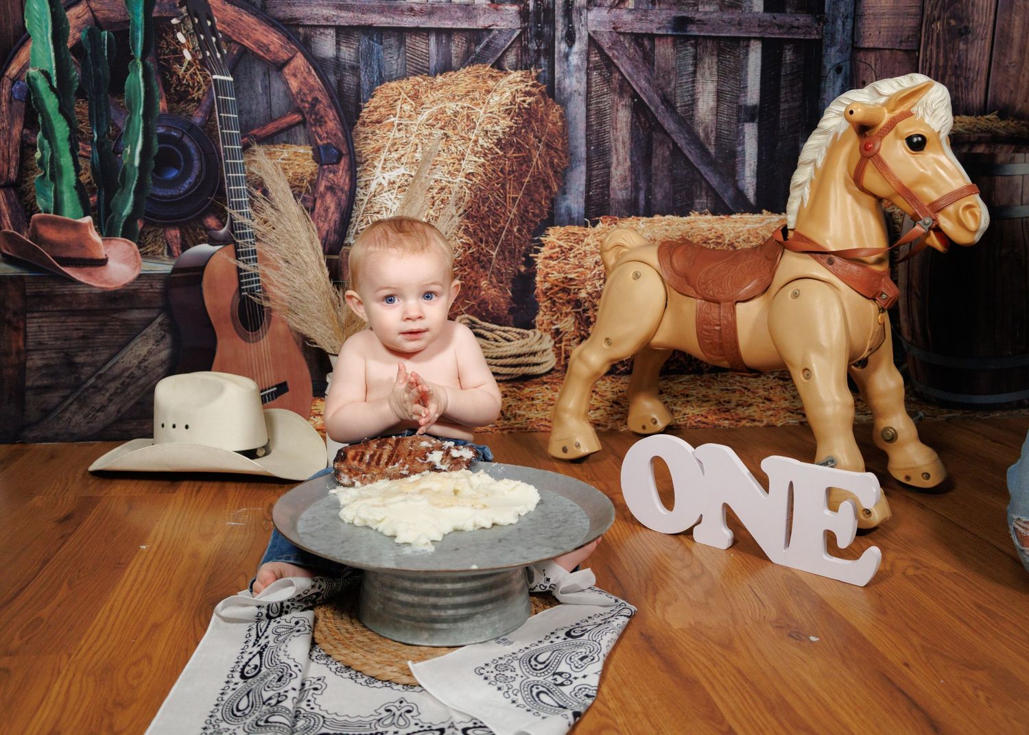 A first birthday cake smash photo session with western-themed props and decorations.