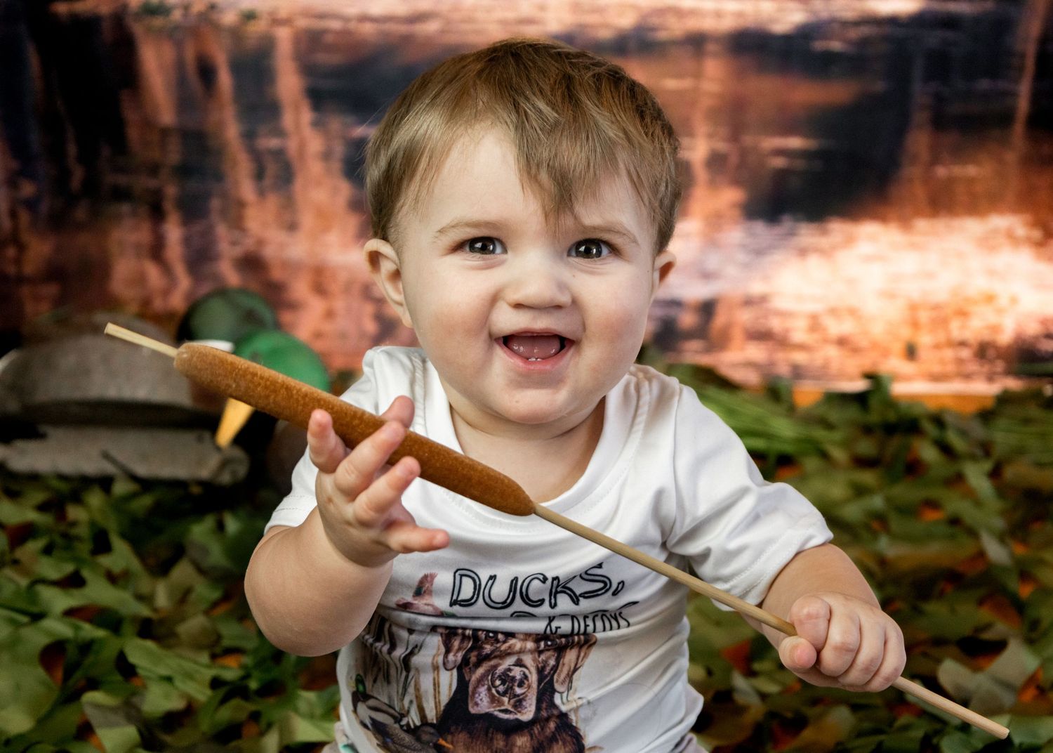 Close-up portrait of a toddler smiling and gesturing while wearing a white t-shirt outdoors.