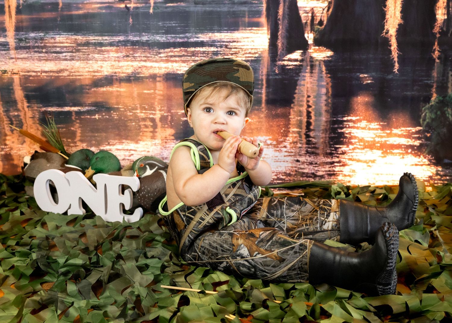Woodland themed first birthday photo session with green balloons and rustic decor.