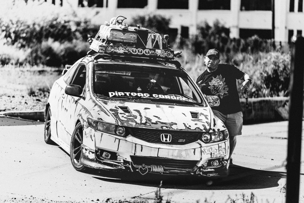 A modified Honda Civic race car with decals and body modifications parked outdoors in black and white photography.