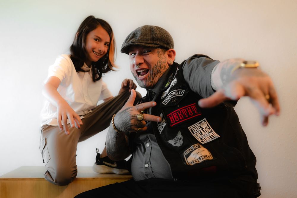 Two musicians perform expressively together with animated gestures during a casual indoor session.