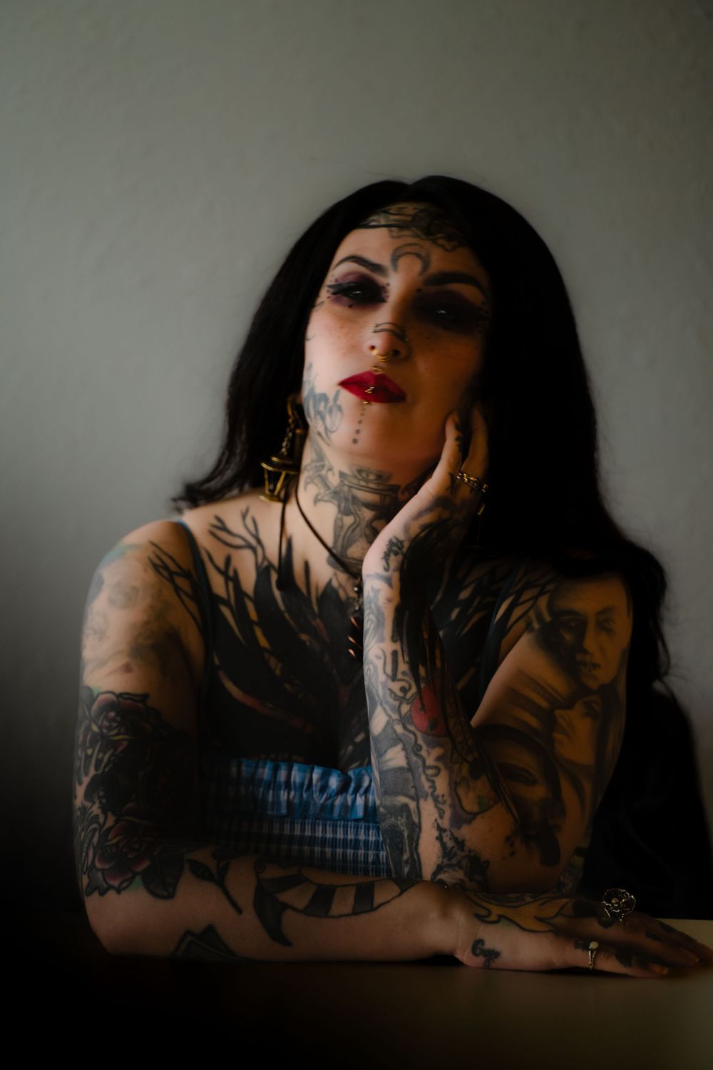 Moody boudoir portraits showing tattooed figure resting on surface in dark atmospheric lighting.