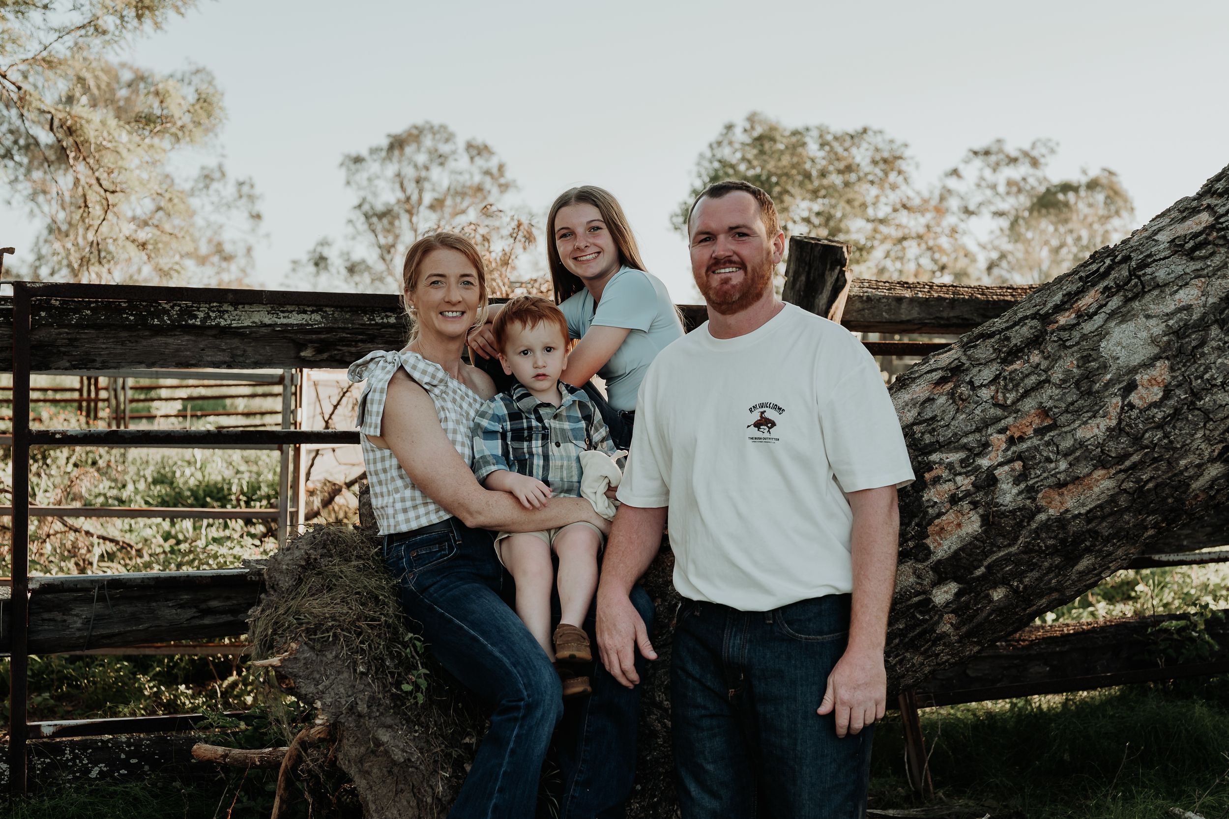 Family portrait session outdoors with rustic wooden fence and natural scenery.