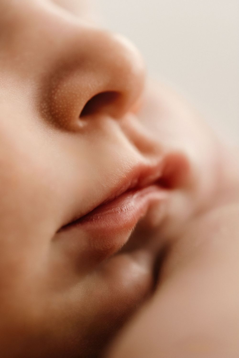 Close-up macro photo of a sleeping baby's nose and lips, showcasing soft, delicate skin texture.