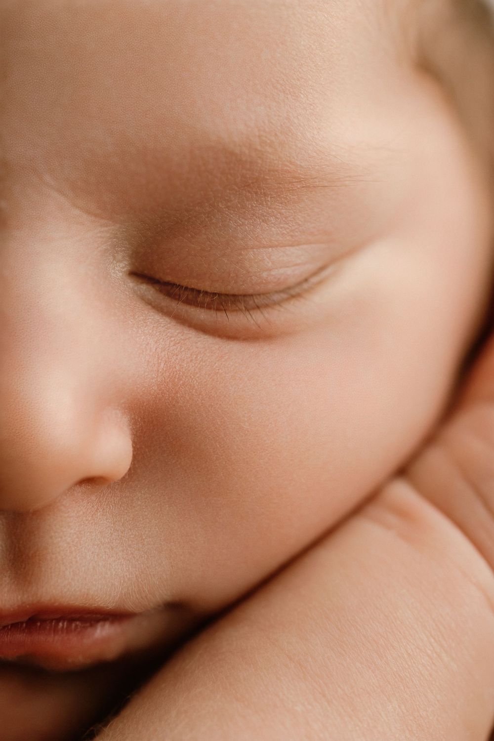 Close-up portrait of a peaceful sleeping newborn baby with delicate features and soft skin.