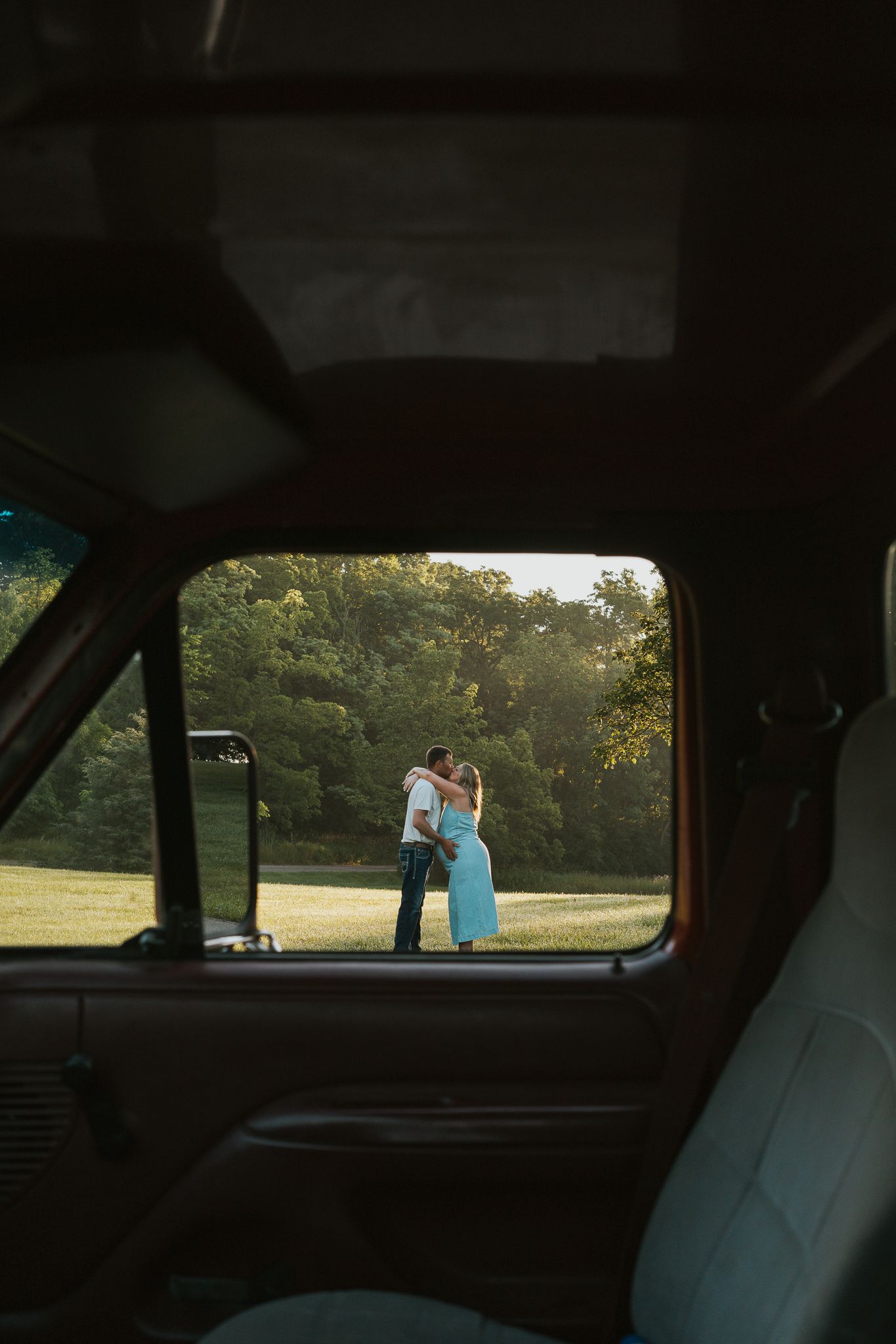 Silhouetted figures visible through car window against sunset backdrop.