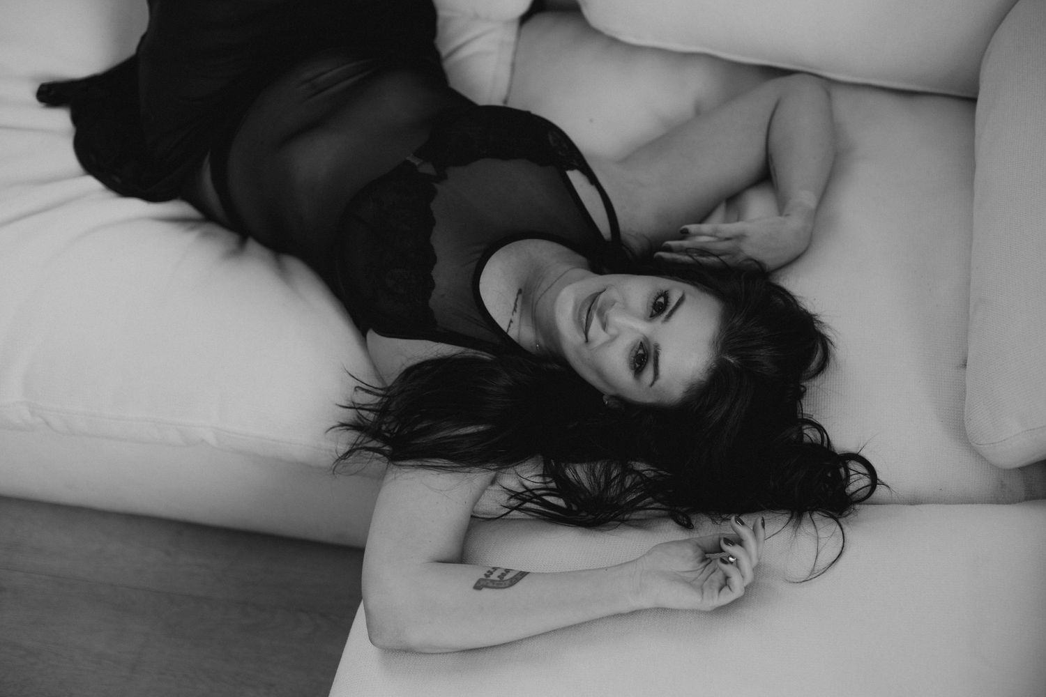 Black and white photo of person resting on bed with natural window light.