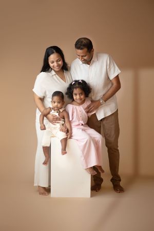 Studio family portrait with parents and children in coordinated white and pink outfits.