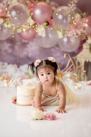 Baby cake smash photography with pink balloon arch and gold accents.