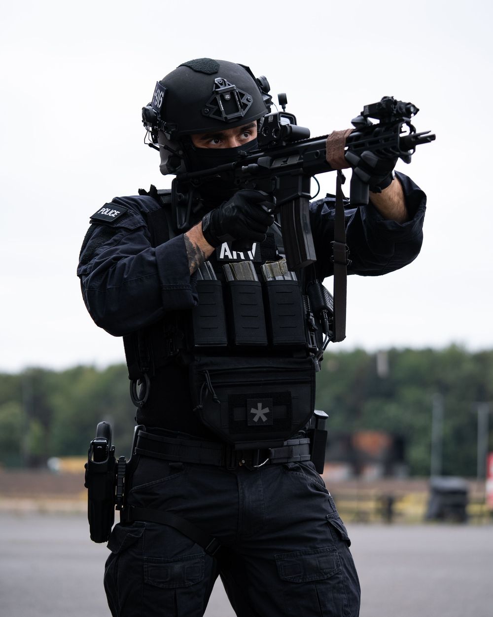 SWAT team members in tactical black gear and helmets aim rifles during a coordinated training exercise.