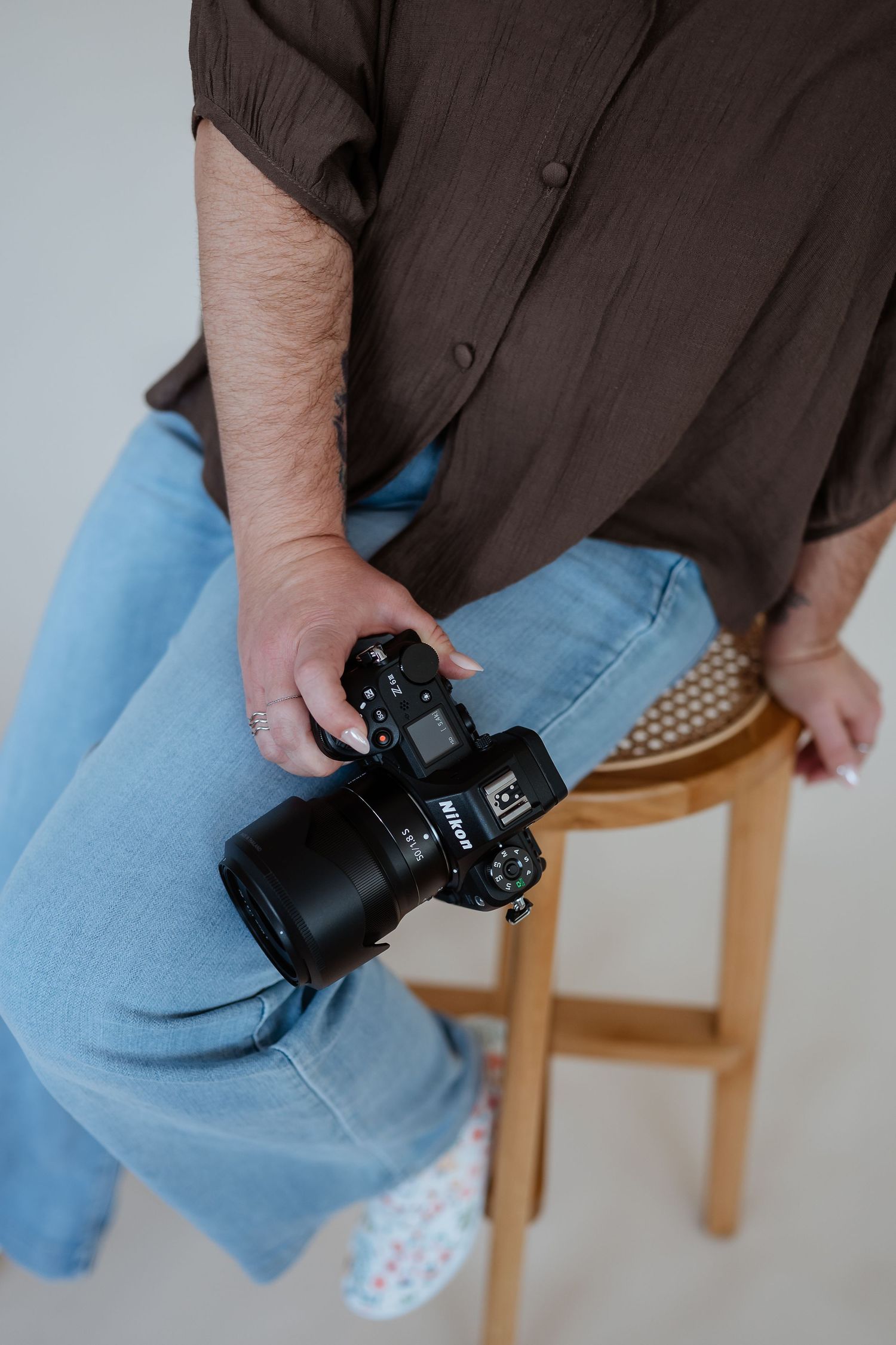 Close-up view of hands holding a black digital camera against blue jeans.