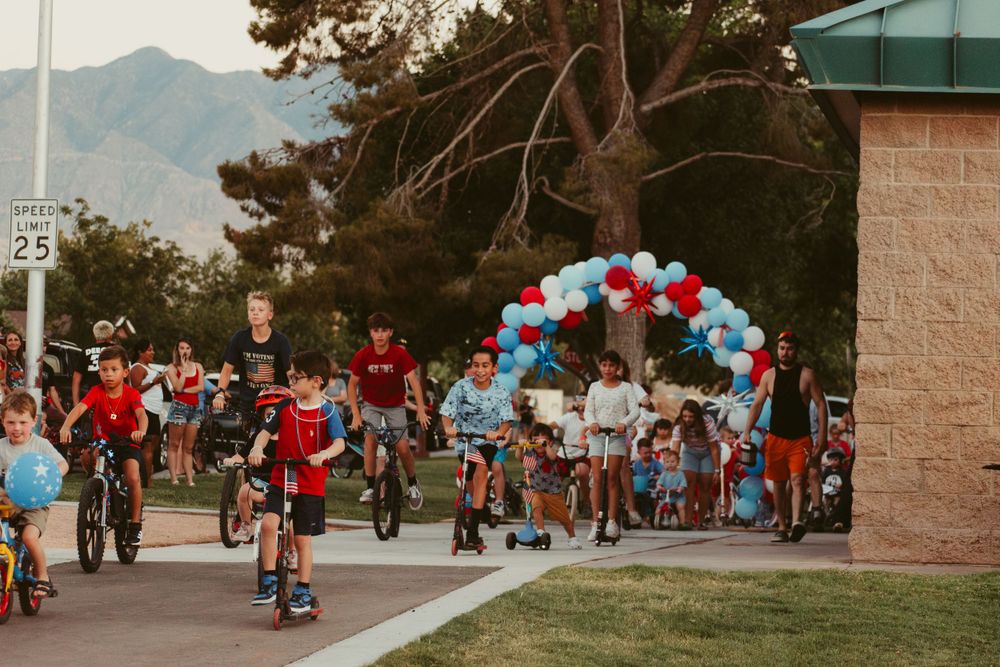 People gathered at an outdoor event with red and blue balloons decorating the venue at sunset.