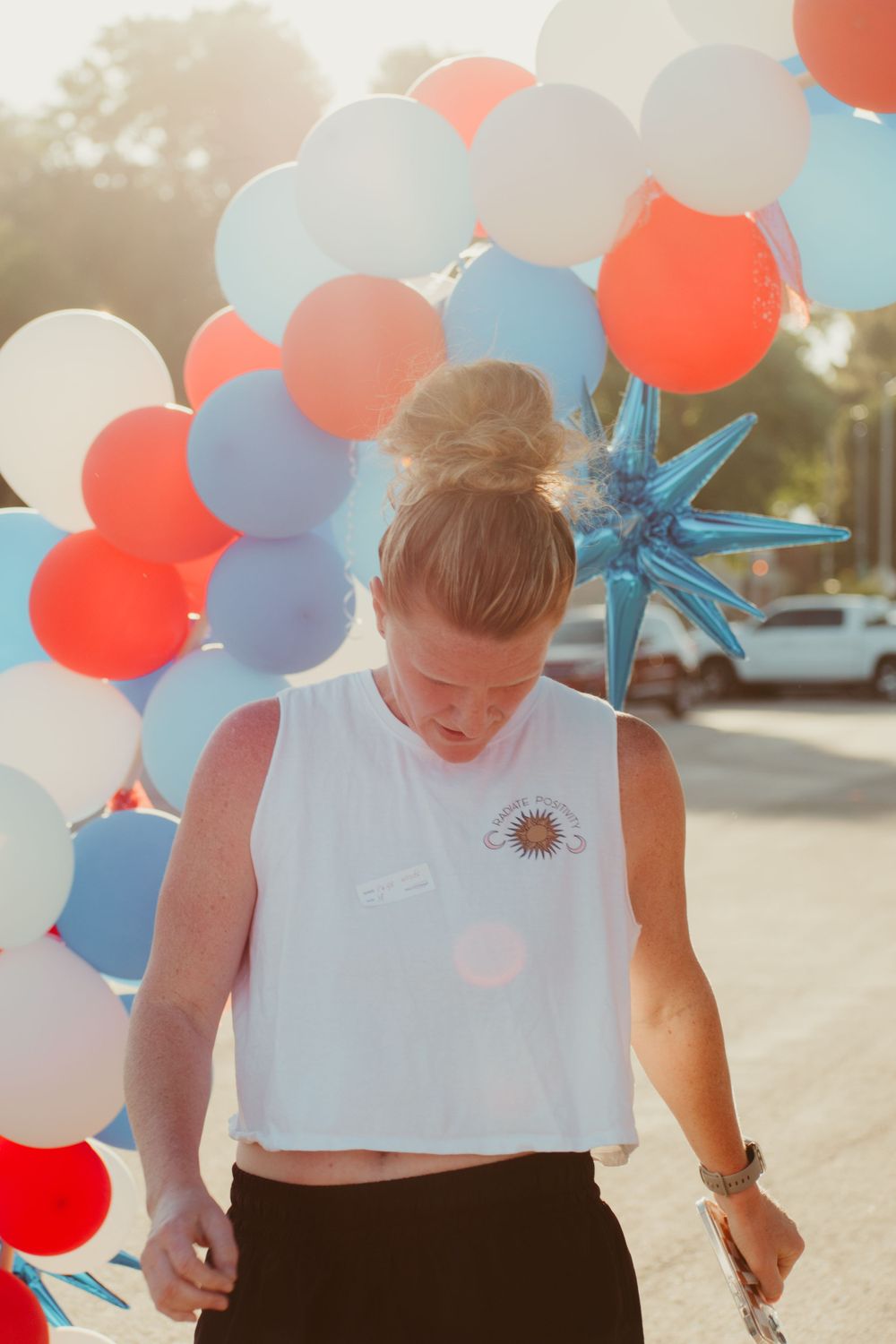 Red and blue balloons float against a sunset sky at an outdoor celebration.