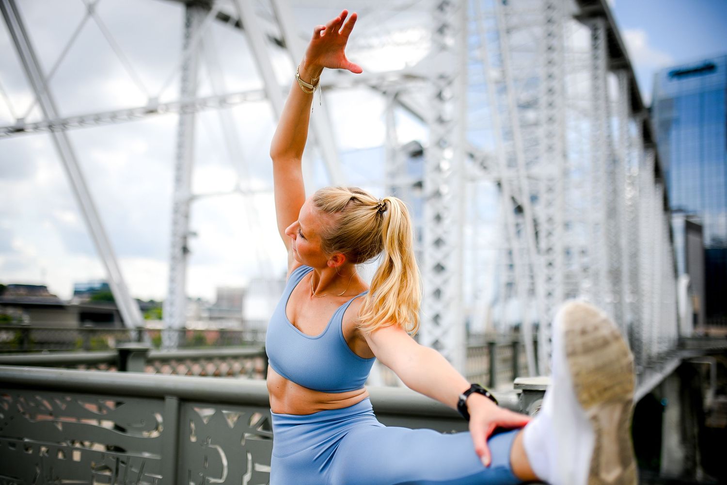 Yoga practitioner stretches in athletic wear on urban bridge during outdoor workout session.