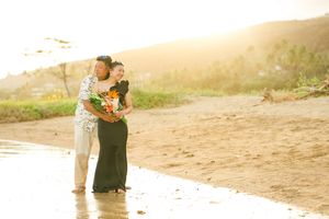 A romantic beach photoshoot at sunset captures a couple in white attire walking along the sandy shore.