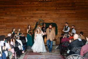 Wedding ceremony exit in rustic wooden barn with guests seated on both sides.