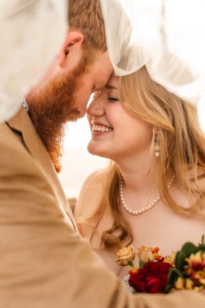 Romantic wedding portrait with couple sharing intimate moment and pearl necklace detail.