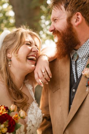 Romantic outdoor wedding moment with joyful laughter and autumn sunlight.