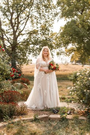 Beautiful autumn wedding scene with bride in lace dress holding vibrant bouquet in garden setting.