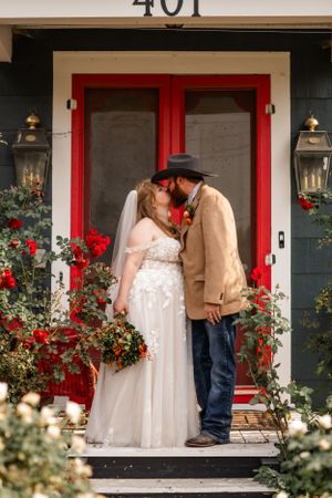 Romantic wedding scene at red doorway with flower gardens and lanterns.