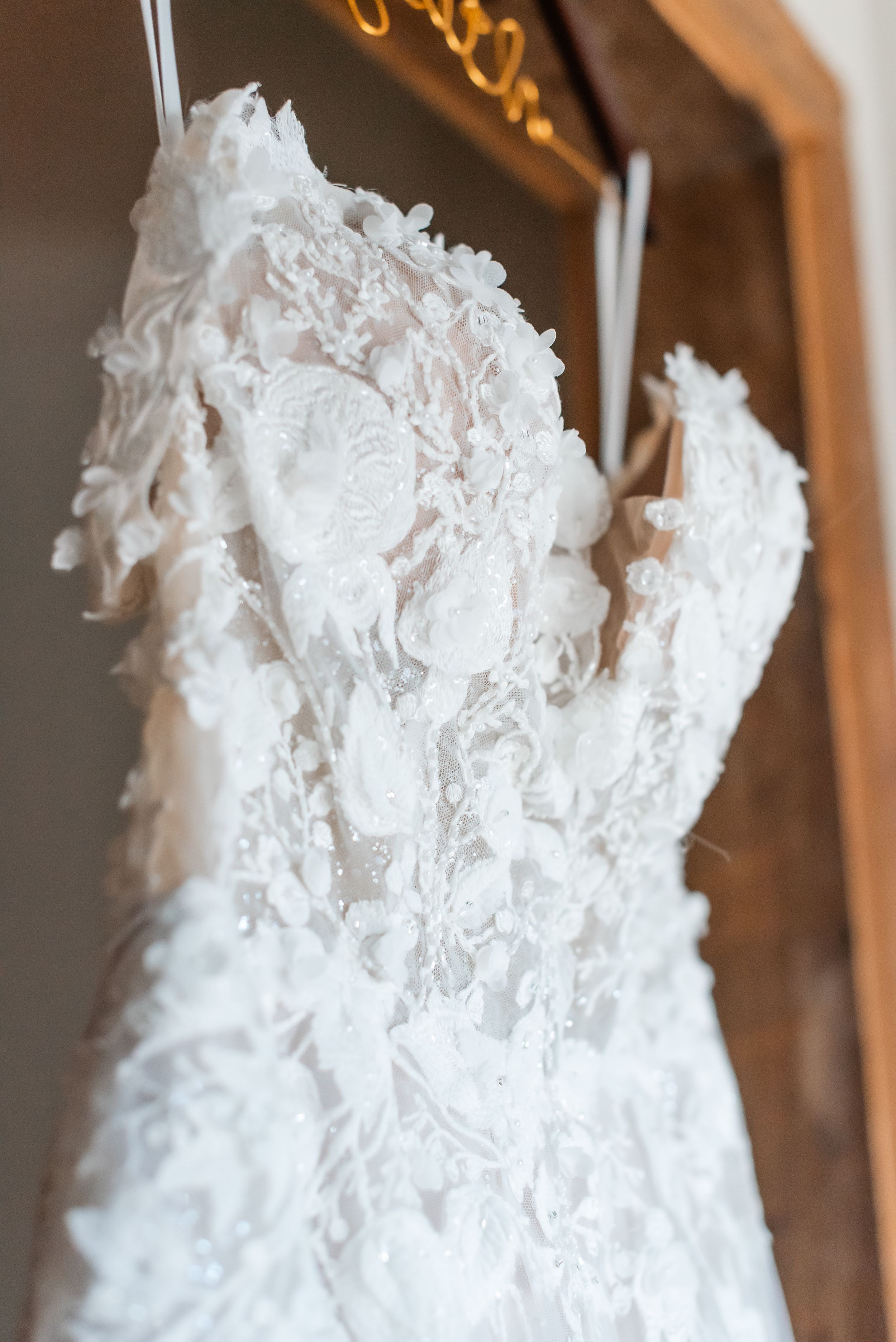 Close-up detail of white lace wedding dress bodice hanging on display.