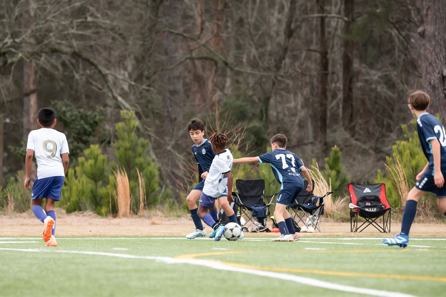 Youth soccer players in action during a competitive match on a grass playing field.