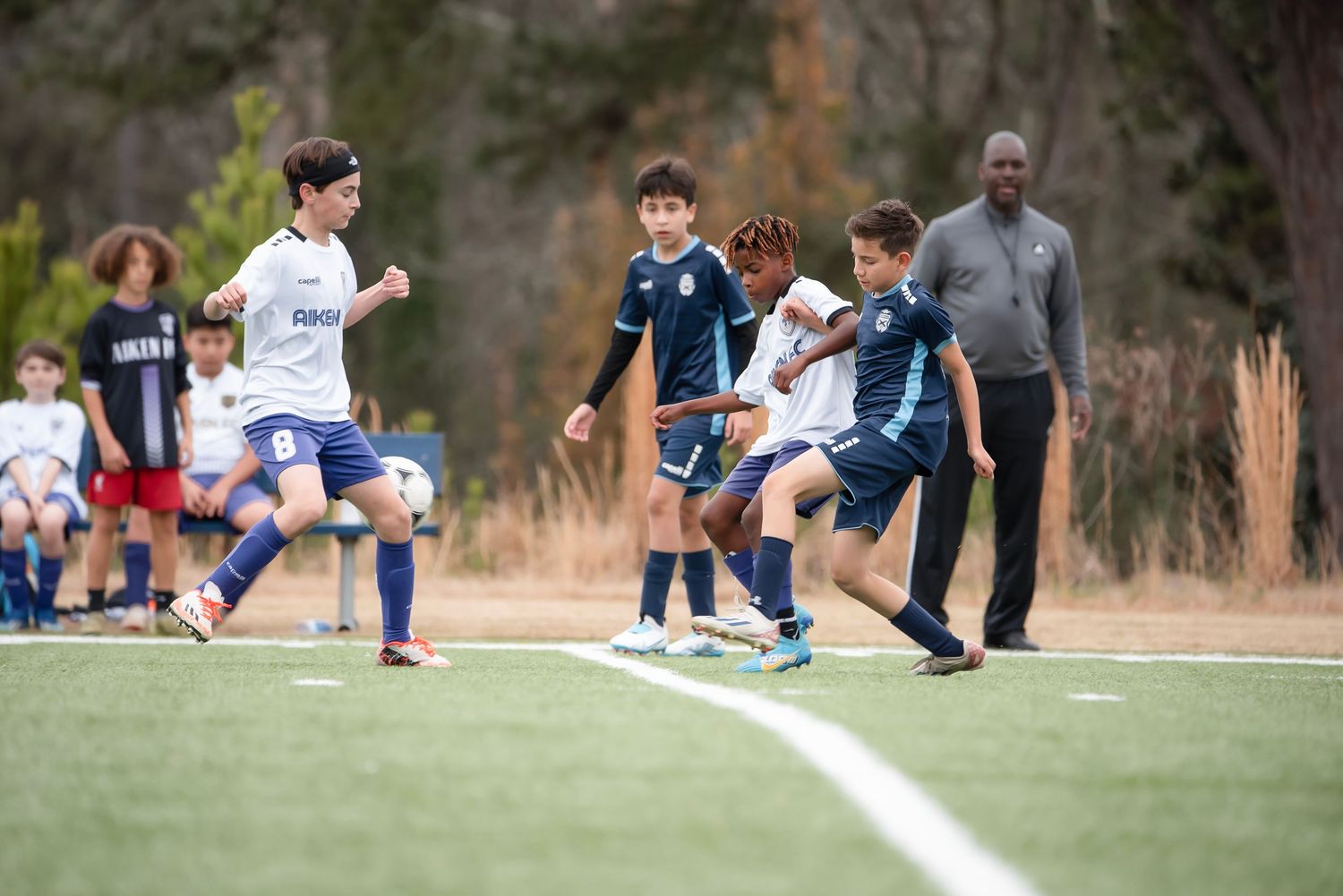 Players from opposing teams compete for control of the soccer ball during a match.