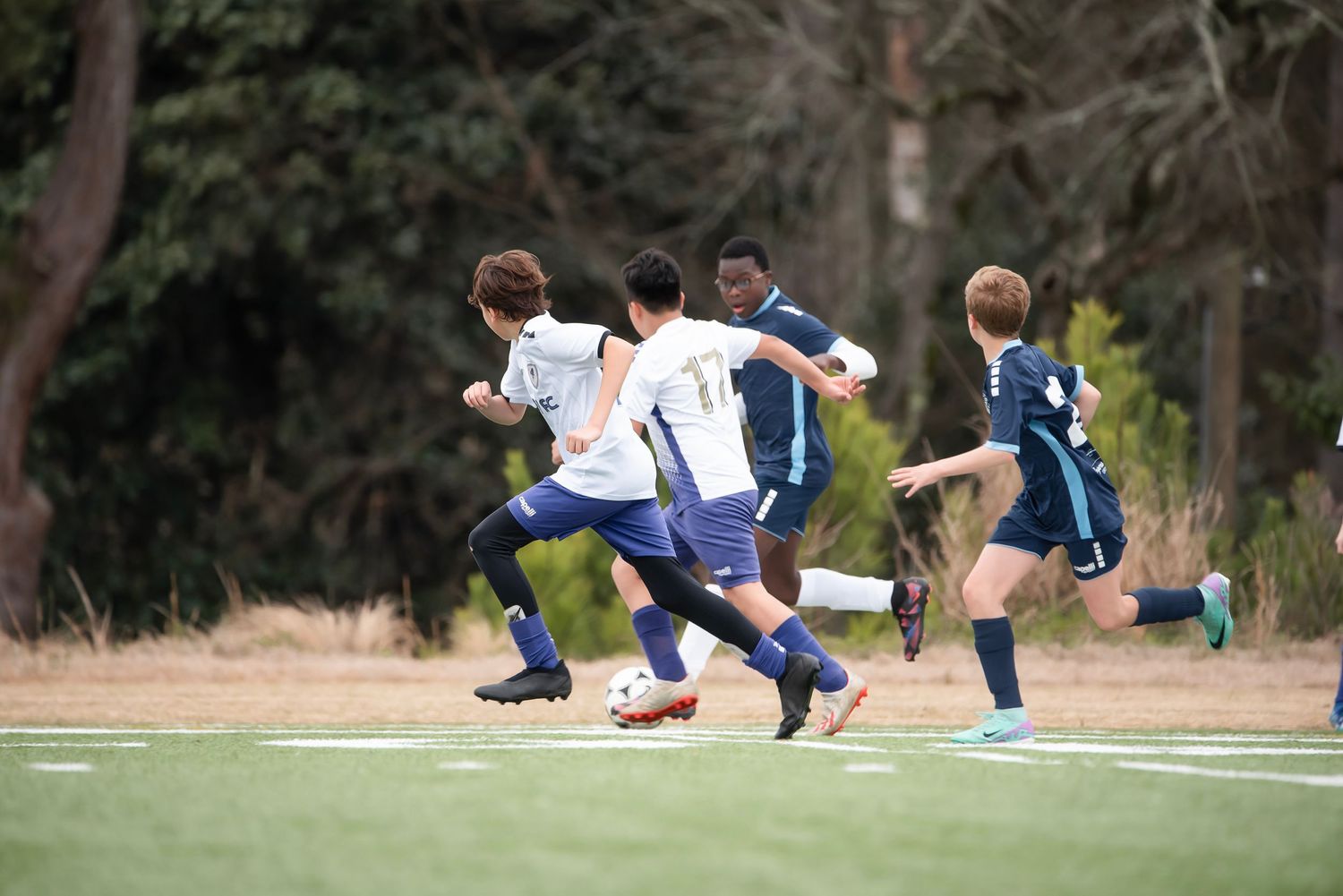 Dynamic soccer action with players sliding and competing for the ball on the grass.