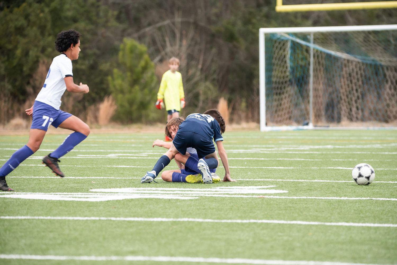 Soccer match scene with players near the goal post during an intense game moment.