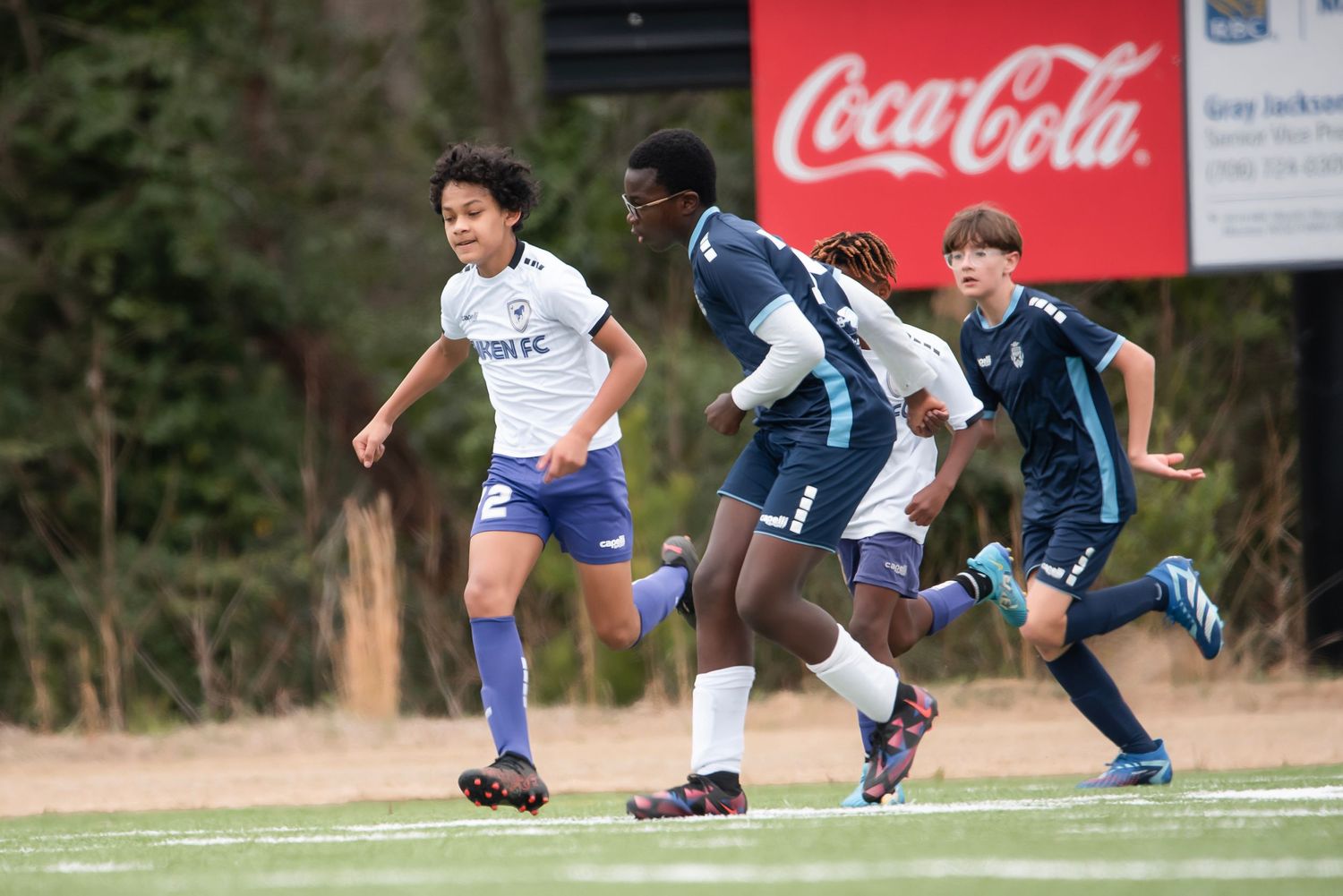 Soccer game with Coca-Cola advertisement banner visible in the background.