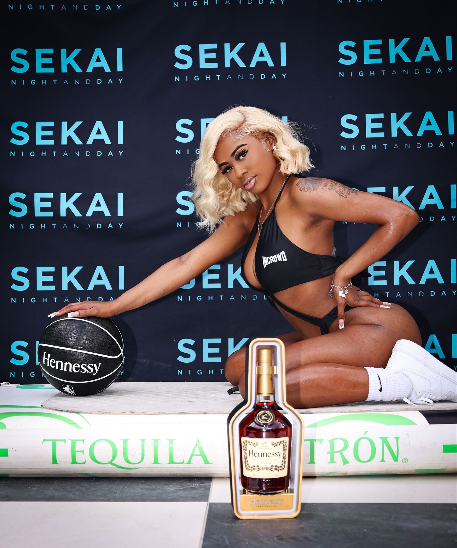 Promotional photo with alcohol bottles and basketball against blue Sekai branded backdrop.