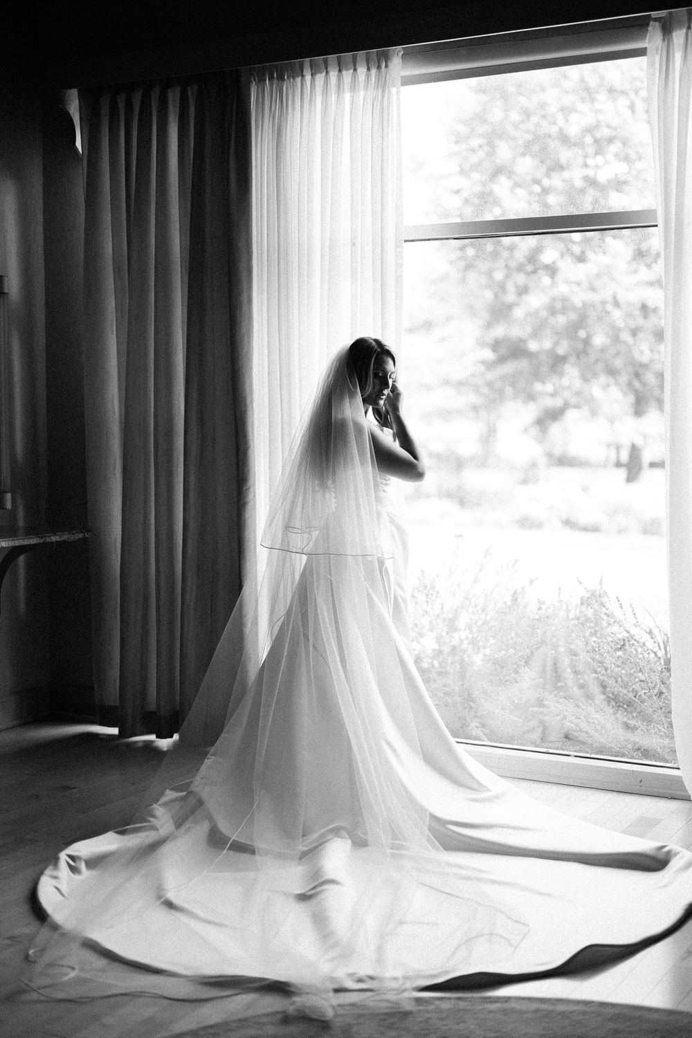 A series of black and white photos showing a bride in a flowing white gown and veil sitting by a window.