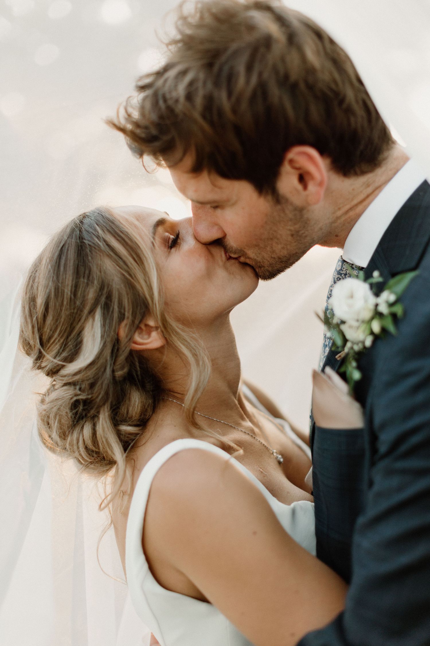 Intimate wedding portrait capturing tender kiss between newlyweds.