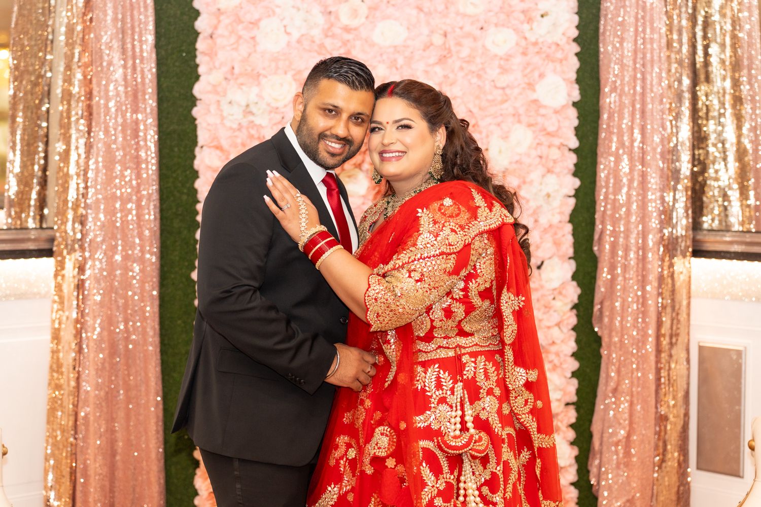 Two people share a romantic moment at a reception venue decorated with white floral garlands.