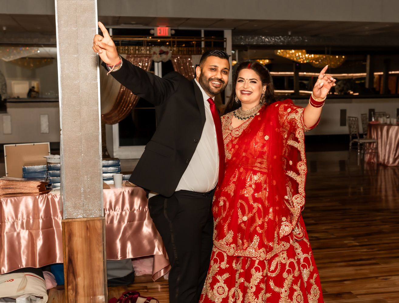 A couple dances together at a wedding reception, with the person wearing a vibrant red traditional dress.