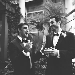 Black and white wedding photo series showing groomsmen laughing and sharing joyful moments in formal attire.