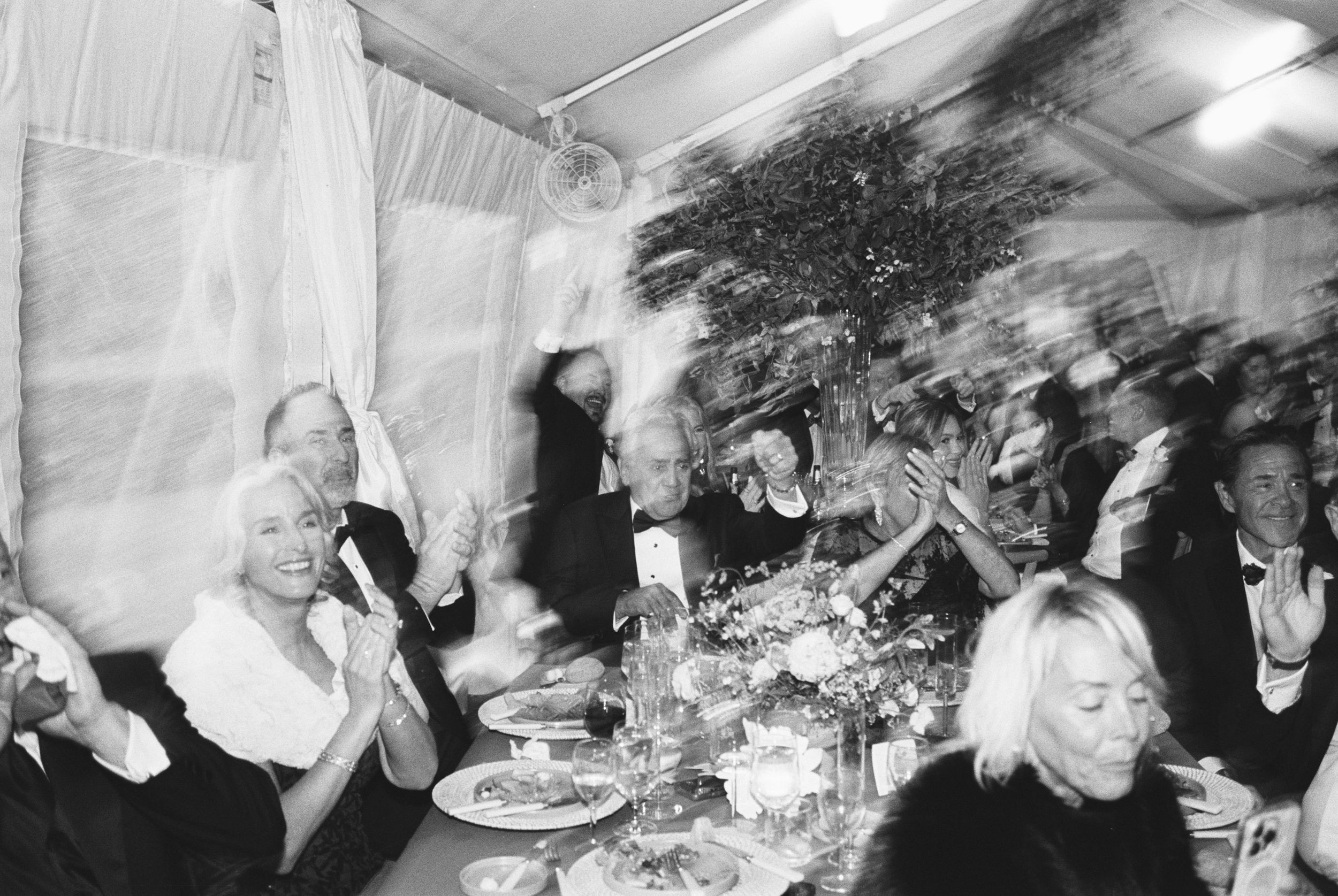 A black and white photo strip showing a sequence of candid party moments with people celebrating and interacting.