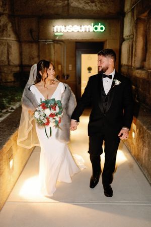 A romantic wedding sequence shows a couple walking through a warmly lit stone corridor with red and white floral bouquet.