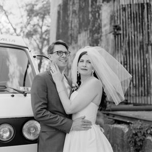 Vintage style black and white outdoor wedding photography showing a couple by a rustic wooden fence.