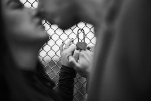 Black and white close-up photos of dogs peeking through chain link fence create emotional connection with viewer.