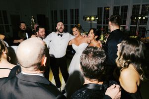 Wedding guests dance and celebrate together on a dance floor during an indoor reception party.