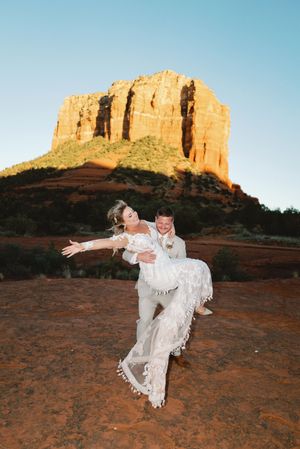 A romantic photoshoot in front of Courthouse Butte in Sedona featuring a white lace dress against the red rock formations.